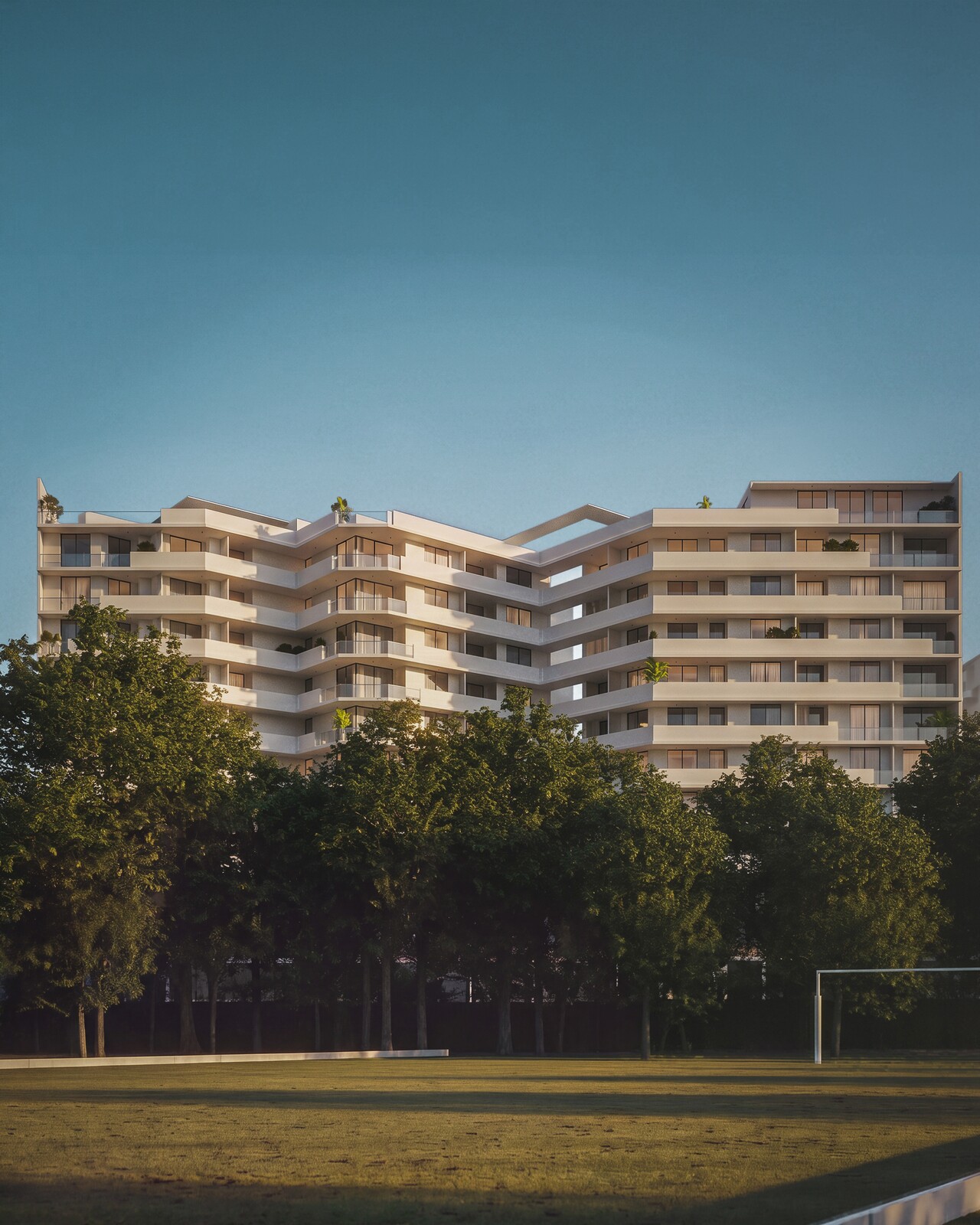 Edificio residencial al atardecer, detrás de la arboleda